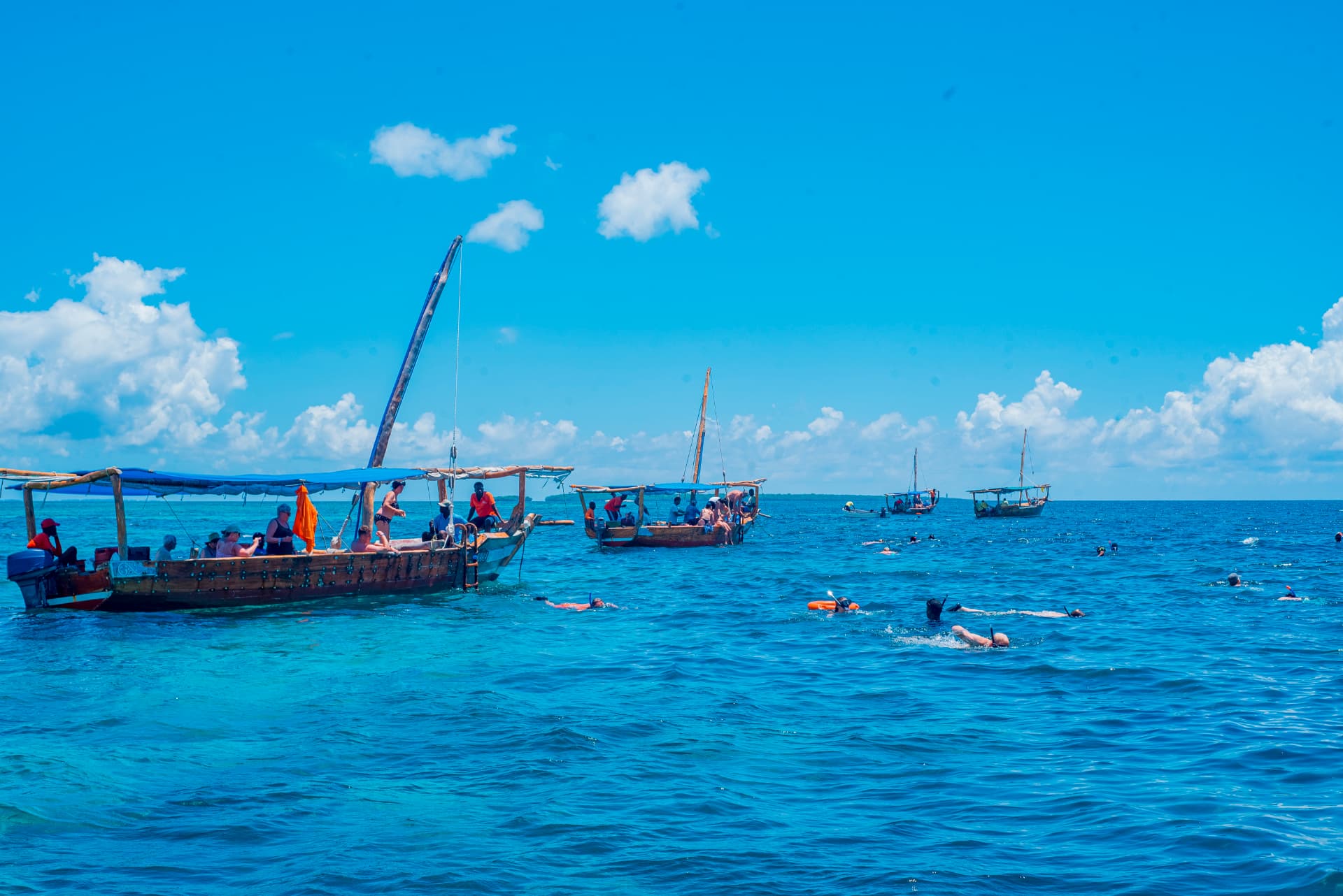 Traditional dhow boats and snorkellers on a clear turquoise sea in Zanzibar