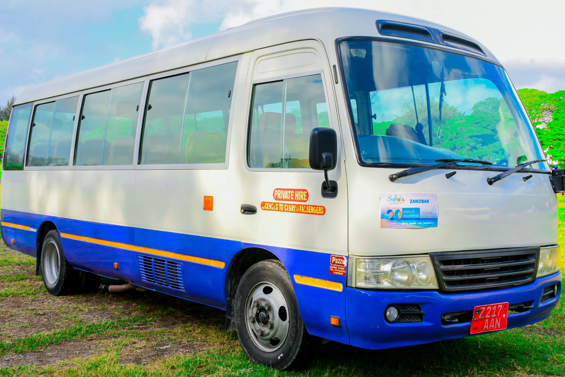 White and blue Toyota Coaster minibus with private hire markings on the lawn