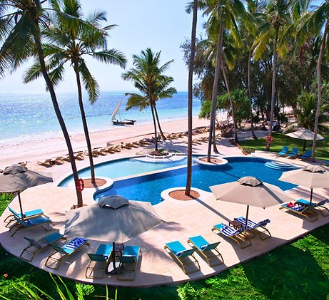 Resort swimming pool with lounge chairs and umbrellas overlooking a beach