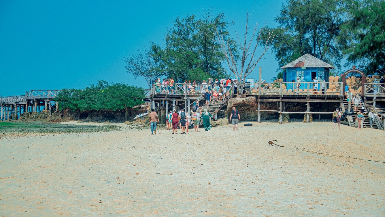 Tourists visiting a coastal area with a wooden boardwalk on Prison Island
