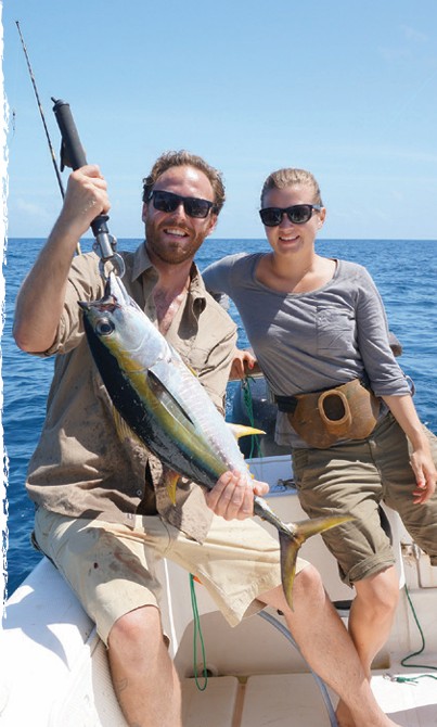 A couple holding a fish on a deep-sea fishing boat